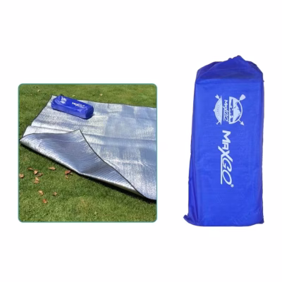 Alfombra térmica MaxGo 200x200 cm extendida sobre el pasto con su bolsa azul